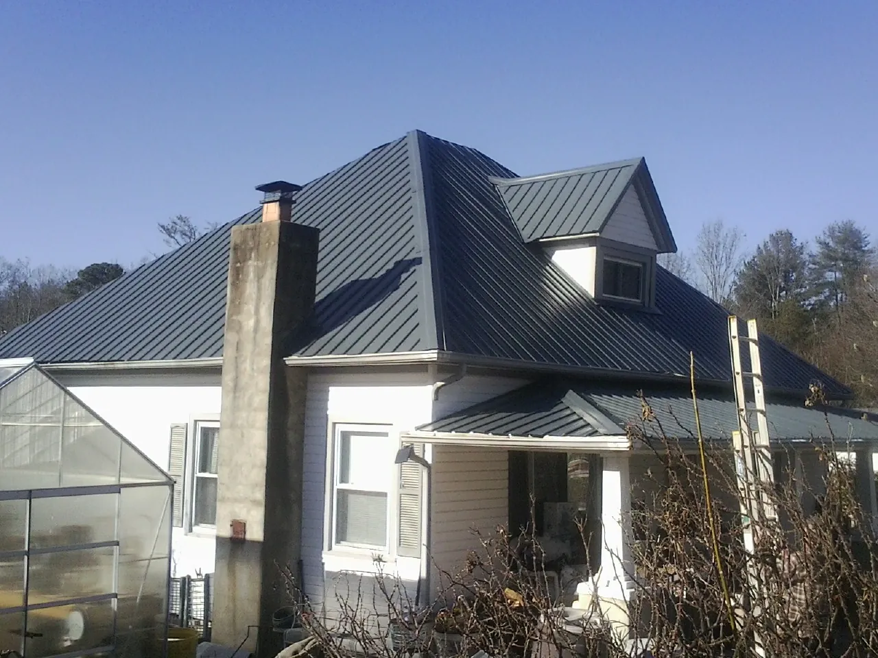 Dark blue standing seam metal roof on a white farmhouse with dormer — Slate & Tile Roof Repair by Roofing Brothers in Coupland