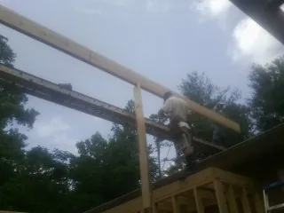 Carpenter setting a ridge beam over a new addition frame — Ice Dam Removal by Roofing Brothers in Coupland