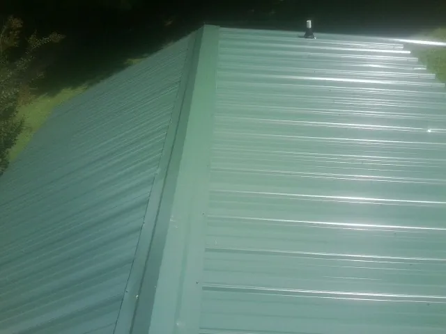 New green metal panels meeting at the ridge of a roof — Flat Roof Repair work by our crew in Coupland