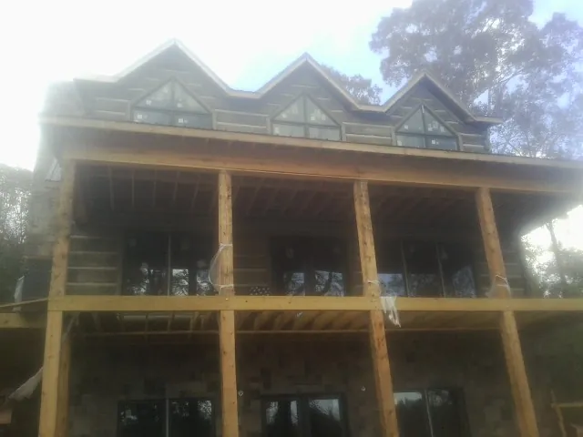 Dormers and porch framing on a large log home under construction — Roof Coating work by our crew in Coupland