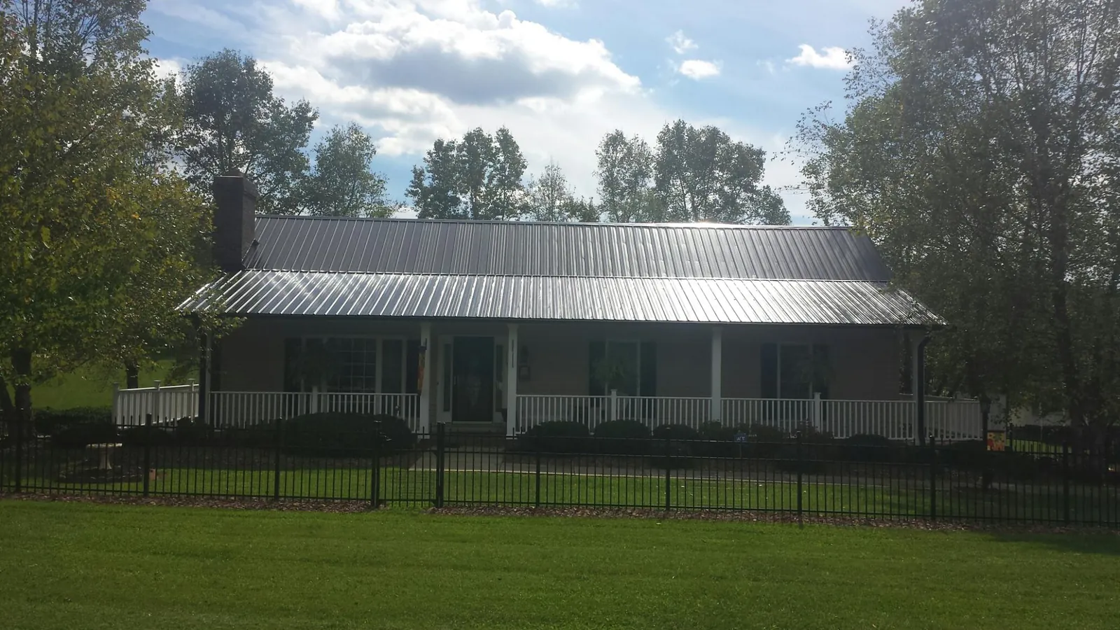 Gray metal roof on a brick ranch with a full width front porch — Gutter Guard Installation work by our crew in Coupland