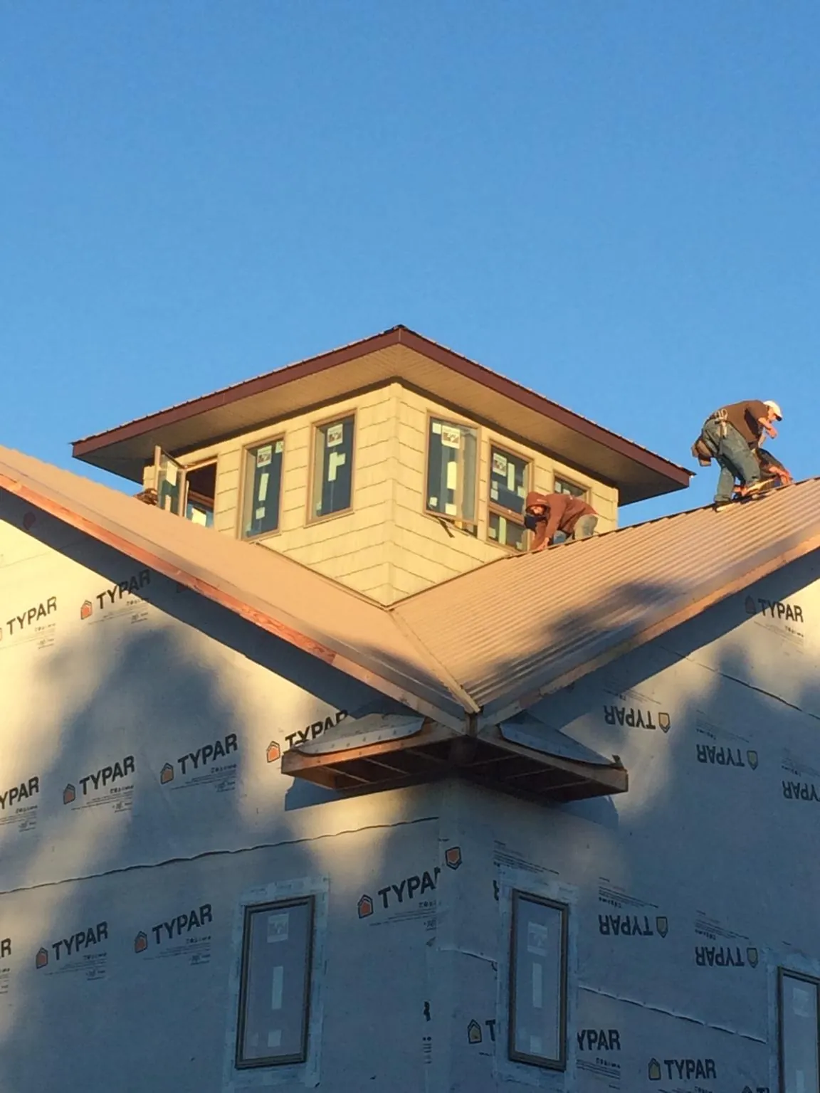 Roofers working around a rooftop cupola on a new metal roof at sunset — Roof Waterproofing in Coupland by Roofing Brothers